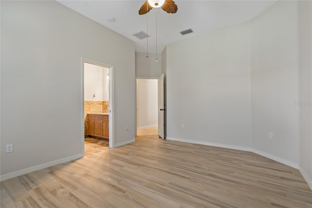 unfurnished bedroom with baseboards, visible vents, light wood finished floors, and connected bathroom