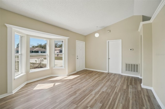 spare room featuring visible vents, vaulted ceiling, a textured ceiling, and wood finished floors