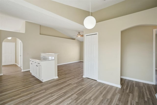 spare room with baseboards, arched walkways, and wood finished floors