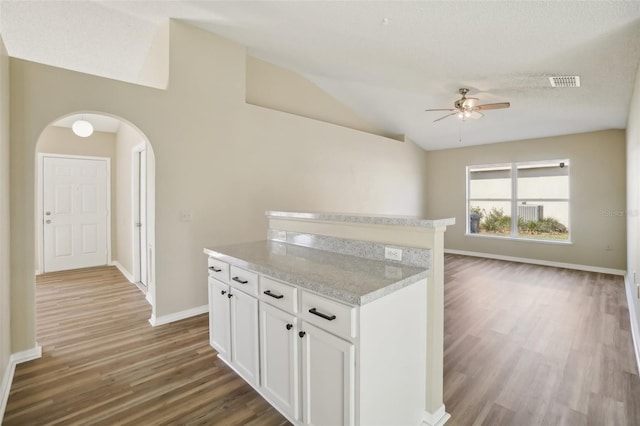 kitchen featuring arched walkways, lofted ceiling, light countertops, visible vents, and open floor plan