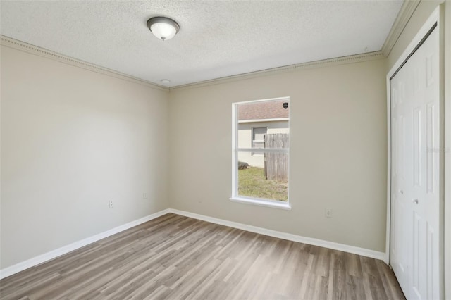 unfurnished bedroom with a textured ceiling, baseboards, a closet, and wood finished floors