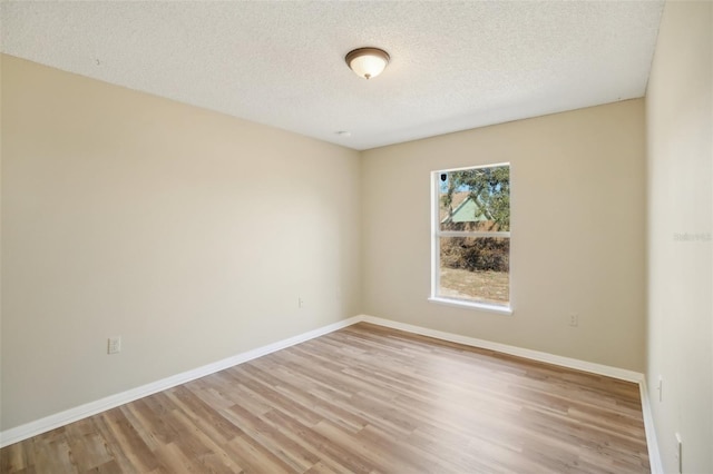 unfurnished room with light wood finished floors, baseboards, and a textured ceiling