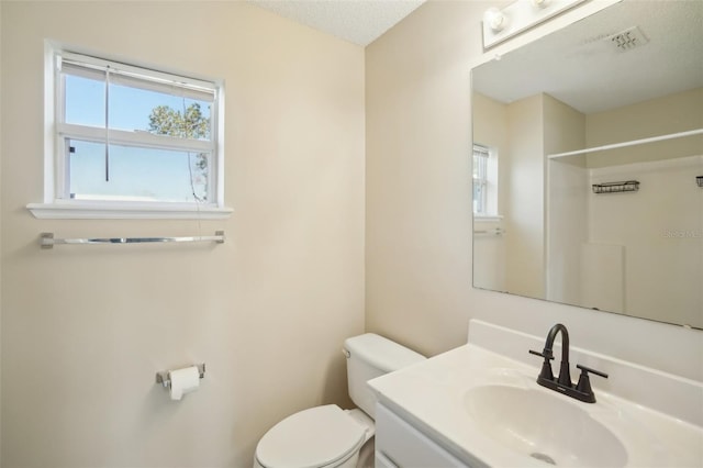 bathroom featuring a textured ceiling, a shower, vanity, and toilet