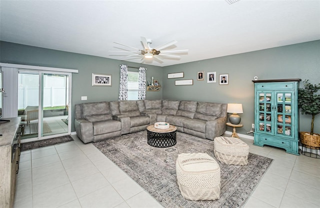 living room with light tile patterned floors, ceiling fan, and baseboards