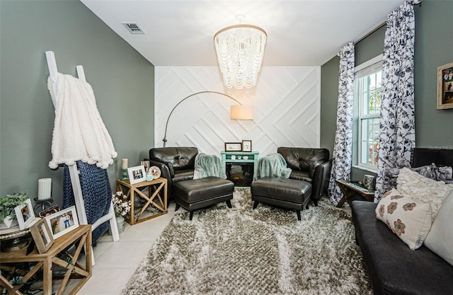 tiled living room with an accent wall, visible vents, and an inviting chandelier