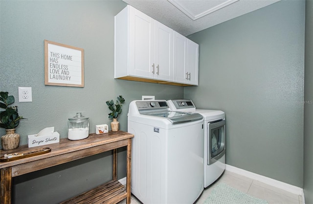 laundry room featuring light tile patterned floors, a textured ceiling, separate washer and dryer, baseboards, and cabinet space