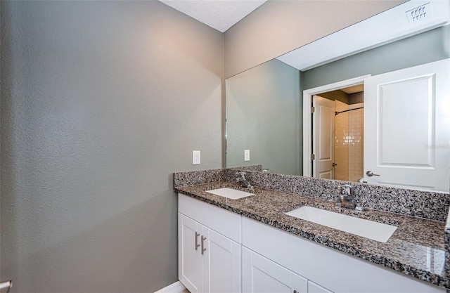 full bath with walk in shower, a sink, baseboards, and double vanity