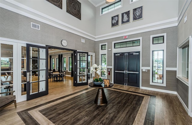 foyer entrance featuring a wealth of natural light, a wainscoted wall, wood finished floors, and french doors