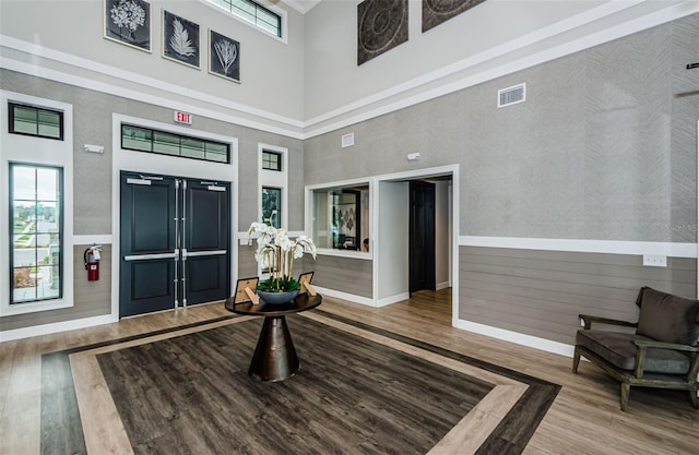 foyer entrance with a wealth of natural light, a high ceiling, visible vents, and wood finished floors