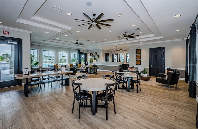 dining room with light wood finished floors, visible vents, and a tray ceiling