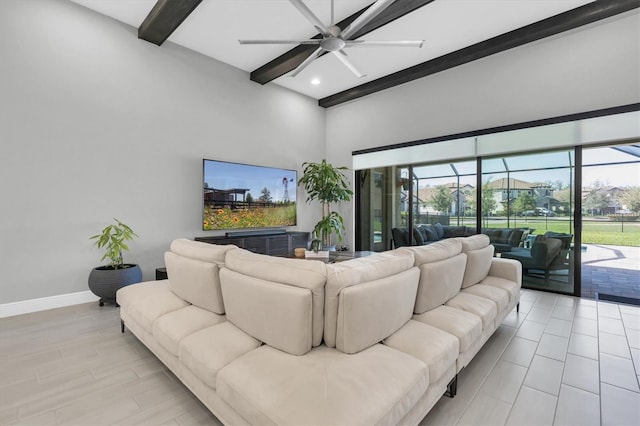 living area featuring beamed ceiling, plenty of natural light, a ceiling fan, and baseboards