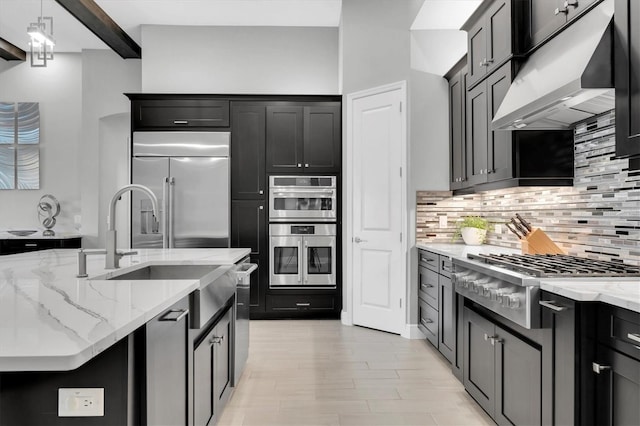 kitchen featuring stainless steel appliances, under cabinet range hood, light stone counters, and tasteful backsplash