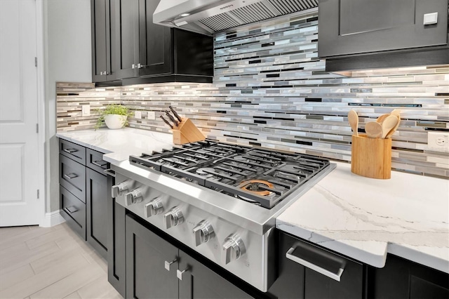 kitchen featuring stainless steel gas cooktop, backsplash, light stone countertops, and custom range hood