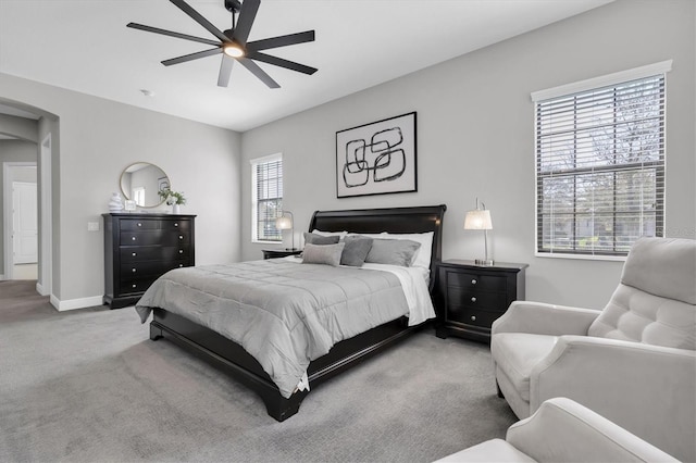 bedroom with arched walkways, carpet flooring, ceiling fan, and baseboards