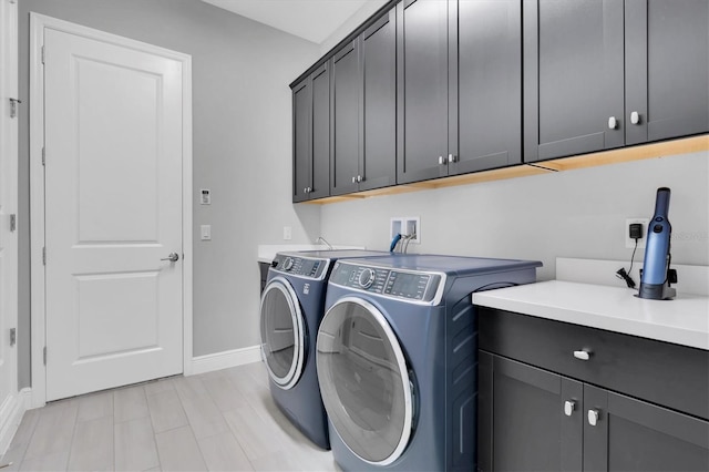 clothes washing area featuring cabinet space, washer and clothes dryer, and baseboards