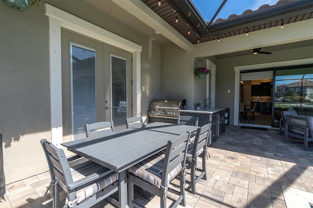 view of patio / terrace with an outdoor kitchen, ceiling fan, a grill, a sink, and outdoor dining space