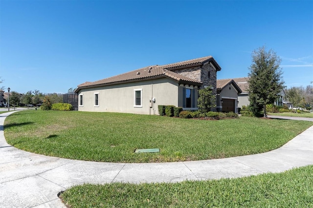 view of side of property featuring a garage, a tile roof, a lawn, and stucco siding