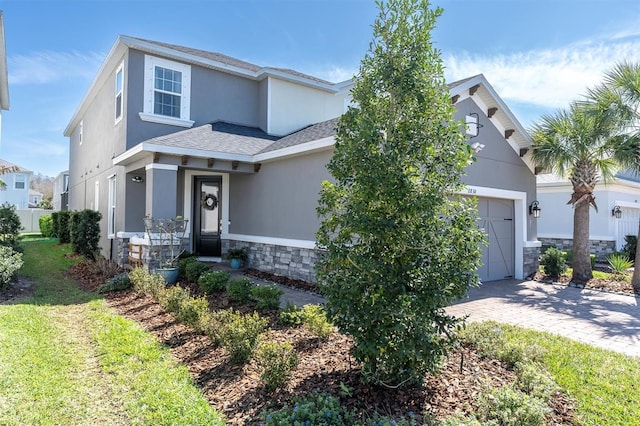 view of front of home featuring a garage, stone siding, decorative driveway, roof with shingles, and stucco siding