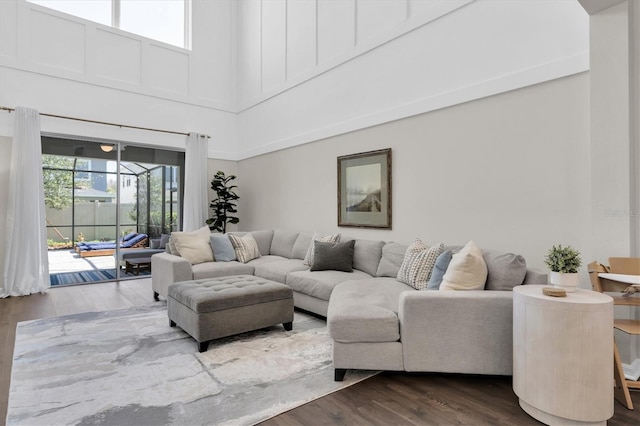 living area featuring a healthy amount of sunlight, dark wood finished floors, and a towering ceiling