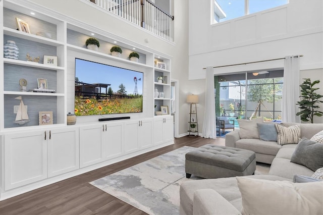 living area featuring a high ceiling, built in features, and dark wood-type flooring