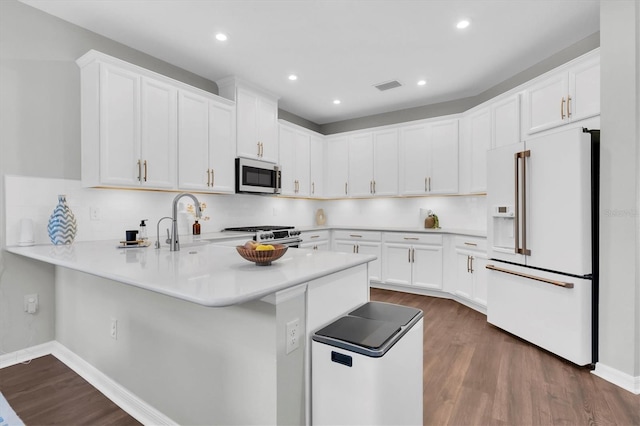 kitchen featuring dark wood-style floors, a peninsula, appliances with stainless steel finishes, and backsplash