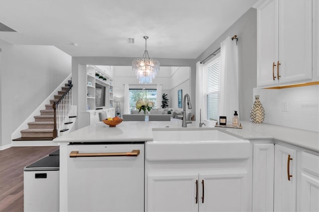 kitchen featuring white dishwasher, a peninsula, a sink, white cabinetry, and open floor plan