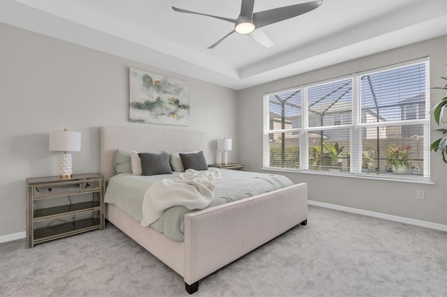 bedroom with a ceiling fan, carpet, baseboards, and a tray ceiling