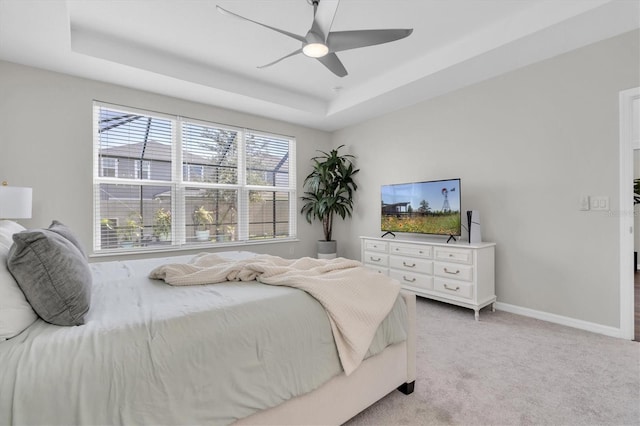 bedroom featuring a ceiling fan, a raised ceiling, light colored carpet, and baseboards