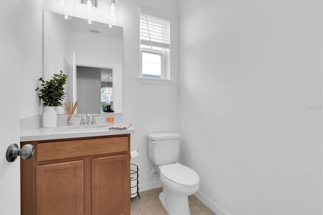 half bathroom with vanity, tile patterned flooring, toilet, and baseboards