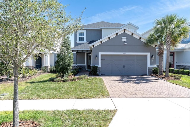 view of front of property featuring a garage, stucco siding, decorative driveway, and a front yard