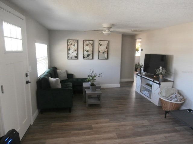 living room featuring dark wood-style floors, ceiling fan, a textured ceiling, and baseboards