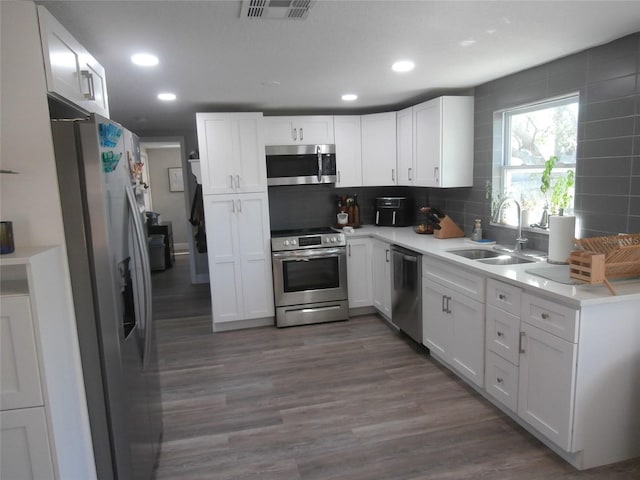 kitchen featuring visible vents, a sink, backsplash, appliances with stainless steel finishes, and white cabinets