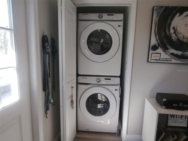 washroom featuring plenty of natural light, laundry area, and stacked washer / dryer