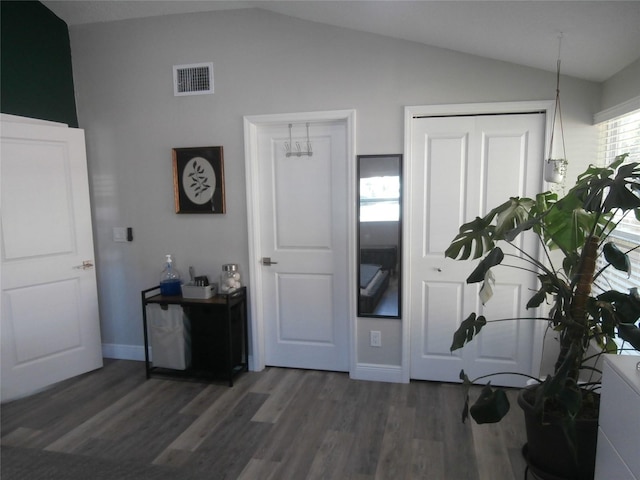 interior space featuring wood finished floors, visible vents, baseboards, vaulted ceiling, and a closet