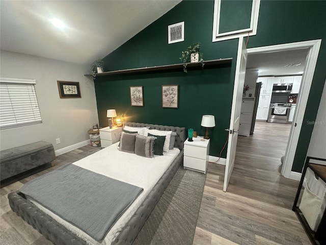 bedroom featuring vaulted ceiling, wood finished floors, visible vents, and baseboards