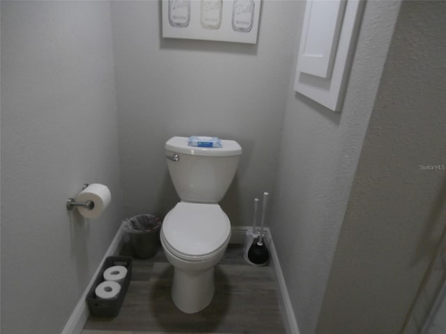 bathroom with toilet, wood finished floors, and baseboards