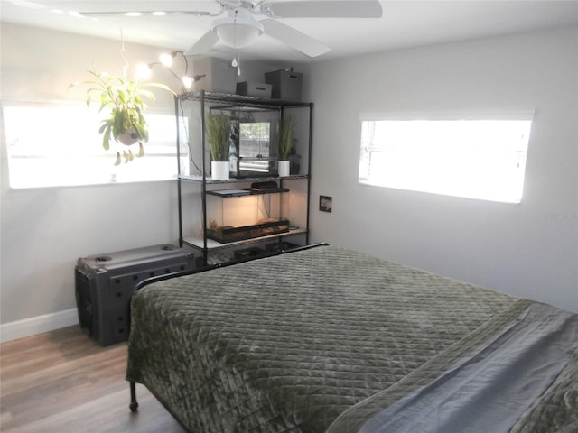 bedroom featuring ceiling fan, baseboards, and wood finished floors