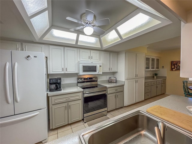 kitchen featuring light tile patterned flooring, white appliances, a sink, a ceiling fan, and light countertops