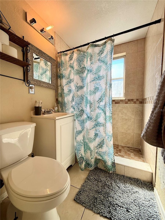 full bathroom with tile patterned floors, toilet, a textured ceiling, a tile shower, and vanity