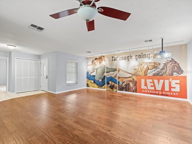 interior space featuring ceiling fan, wood finished floors, visible vents, and baseboards