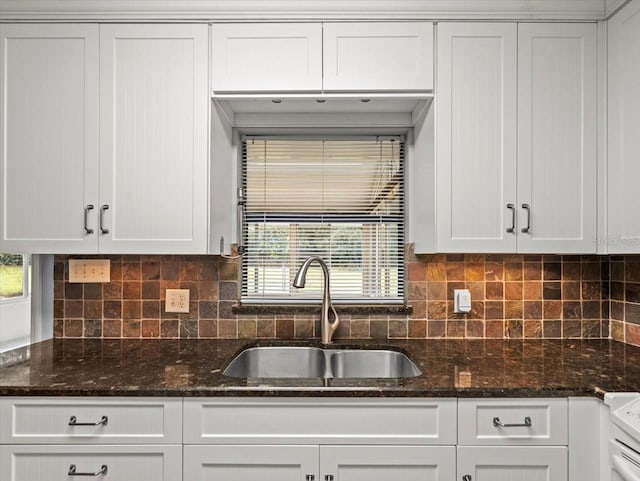 kitchen with dark stone counters, white cabinetry, a sink, and decorative backsplash