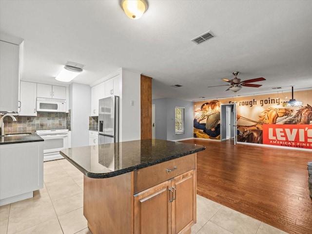 kitchen featuring light tile patterned flooring, white appliances, a sink, visible vents, and backsplash