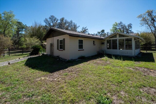 back of house with a sunroom, fence, and a lawn