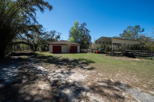 view of yard featuring an outbuilding, fence, and a detached carport