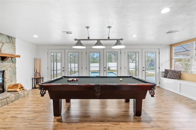 playroom with french doors, a fireplace, visible vents, and light wood-style floors