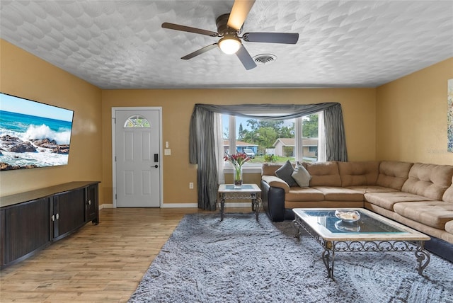 living area with baseboards, visible vents, a ceiling fan, a textured ceiling, and light wood-type flooring