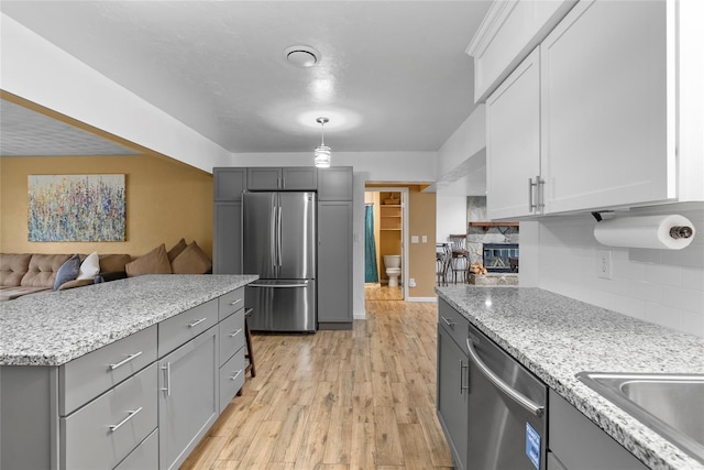 kitchen with stainless steel appliances, backsplash, light wood-type flooring, and gray cabinets