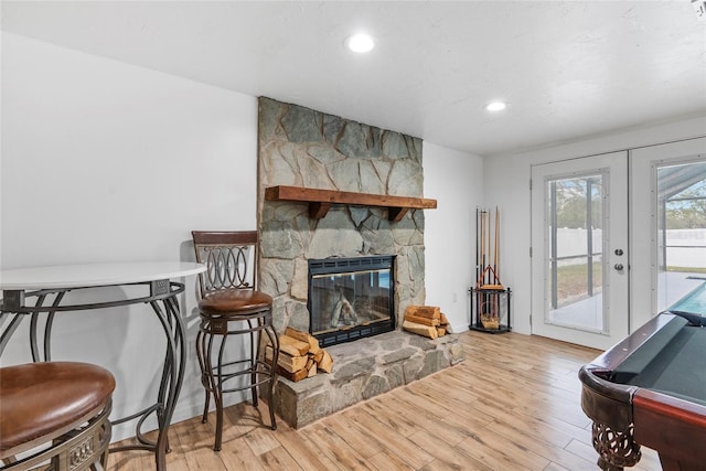 living area featuring french doors, a stone fireplace, wood finished floors, and recessed lighting