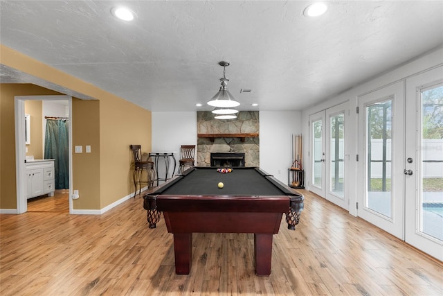 playroom with light wood finished floors, recessed lighting, pool table, a stone fireplace, and baseboards