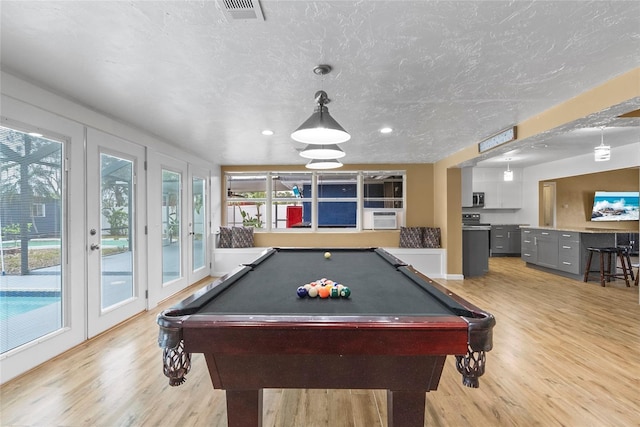 recreation room with a textured ceiling, cooling unit, recessed lighting, visible vents, and light wood finished floors